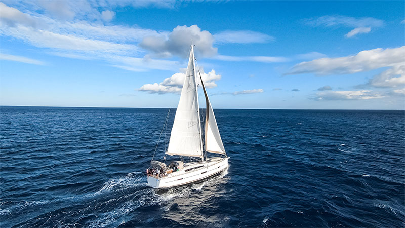 Segla i Medelhavet med bild p segelbt mitt ute i havet. Lite molnigt men fint vder. Ngra personer syns i bakre delen av bten.